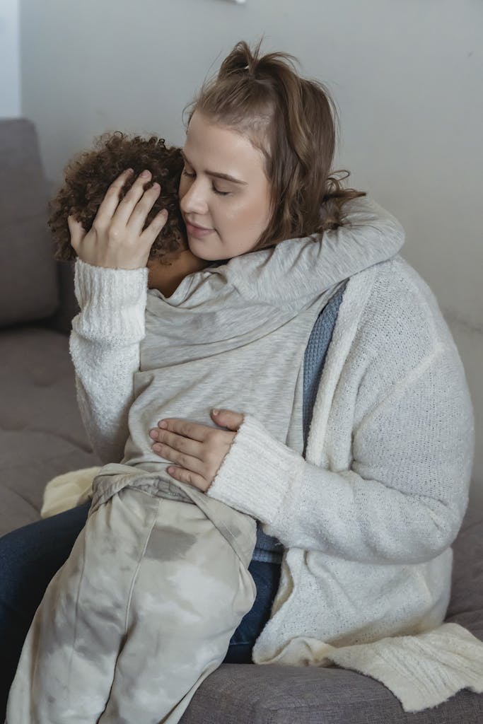 Loving mother comforting crying son on couch